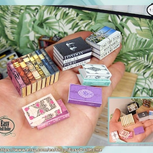 Może przedstawiać: Kolekcja miniaturowych książek w różnych kolorach i wzorach, w tym stos książek z kwiatowym wzorem, stos książek z czarno-białym wzorem i stos książek z zielono-białym wzorem. Książki są w skali 1:12.