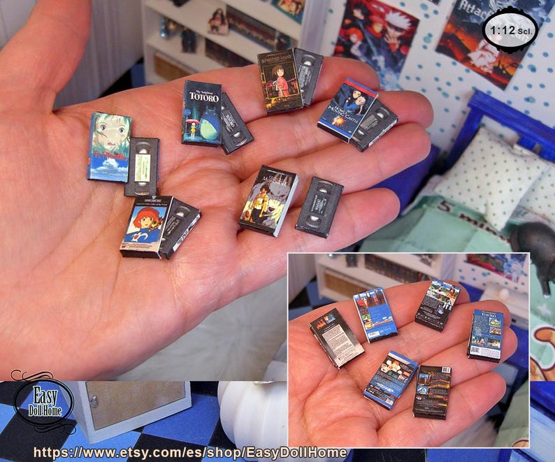 May include: Miniature VHS tapes and movie covers are held in a hand. The tapes and covers feature colorful anime-style artwork. The collection includes titles like "My Neighbor Totoro" and other animated films. The scale is 1:12.