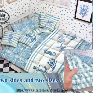 Puede incluir: Juego de ropa de cama en miniatura para casa de muñecas con temática náutica. El juego incluye un edredón, almohadas y una colcha reversible, todos con diseños de olas, rayas, caballitos de mar, estrellas de mar y anclas azules y blancas. El texto "two sides and two sizes" es visible.