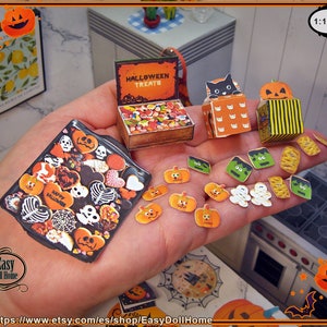 May include: A miniature Halloween-themed dollhouse scene with a tray of cookies, a candy store, and a variety of Halloween-themed decorations. The decorations include pumpkins, ghosts, and bats. The text "HALLOWEEN TREATS" is visible on the candy store.