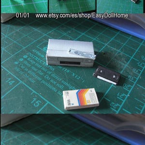 May include: A miniature paper craft VCR, VHS tapes, and remote control. The VCR is silver and gray, with a black tape and a remote. The VHS tapes have colorful stripes. The image shows the steps of cutting and folding the paper.