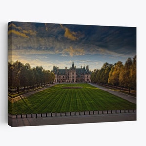 May include: A large, stone mansion with a symmetrical facade and a green lawn in front. The mansion has a pointed roof and many windows. The lawn is surrounded by trees and a fence. The sky is cloudy and the sun is setting.