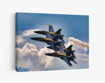 Puede incluir: Cuatro aviones de combate azules y amarillos vuelan en formación contra un cielo nublado. Los aviones dejan estelas de humo blanco.