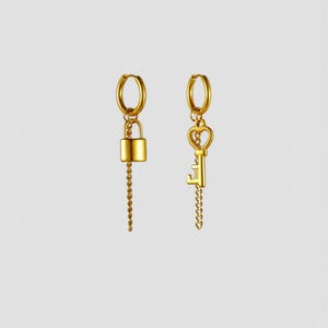 May include: A pair of gold-toned hoop earrings featuring dangling charms. One earring displays a small padlock charm attached to a short chain, while the other earring features a heart-shaped key charm with a matching short chain extension.