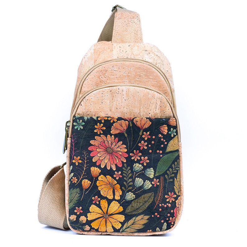 May include: A tan cork sling backpack featuring a front pocket with a dark navy blue background and a vibrant floral print. The bag includes a beige adjustable strap, a top zipper closure, and a secondary zipper for the main compartment.