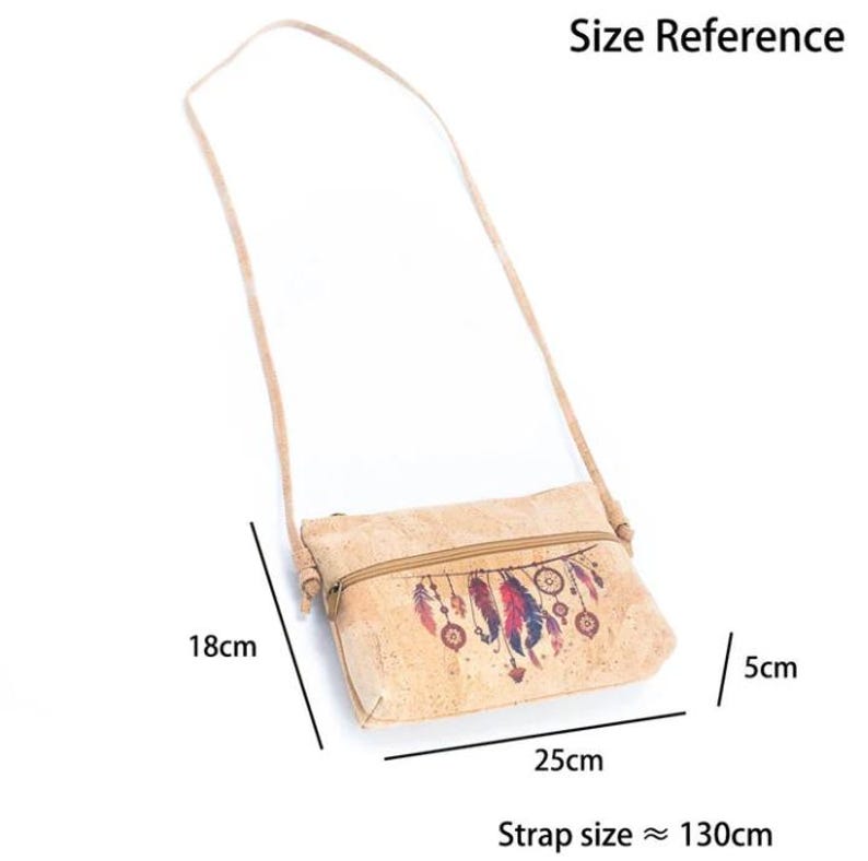 May include: A light brown cork crossbody bag with a zipper closure and a long strap. The bag features a dreamcatcher design with red, blue, and purple feathers. The bag is 25cm wide, 18cm high, and 5cm deep, with a strap approximately 130cm long.
