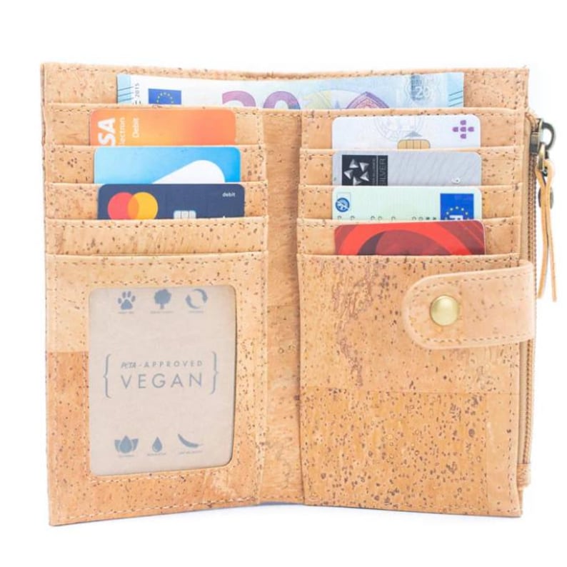 May include: Open brown cork wallet with multiple card slots and a zippered compartment. The wallet has a snap closure and a window for a photo or ID. The wallet is labeled "PETA Approved Vegan".