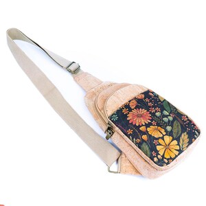 May include: A crossbody sling bag made of light brown cork material featuring a front panel with a dark navy blue background printed with a vibrant floral pattern of orange, yellow, and green flowers and leaves, including a beige adjustable strap.