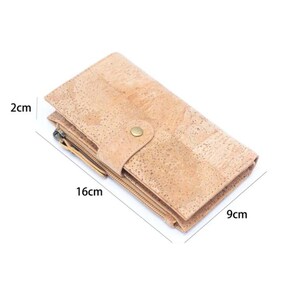 May include: A light brown cork wallet with two zippers and a button closure. The wallet measures 9 inches by 16 inches by 2 inches.