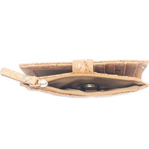 May include: A light brown cork wallet with a zippered coin pocket. The wallet is open and a coin is visible inside the pocket.