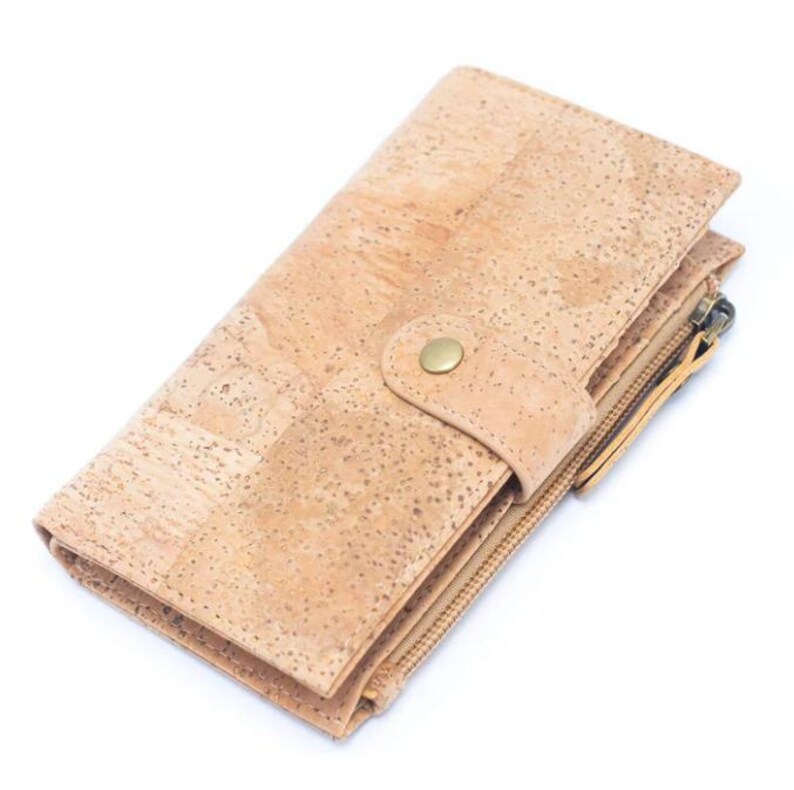 May include: A light brown cork wallet with a zipper closure and a snap closure. The wallet has a textured surface and a gold-colored zipper pull.