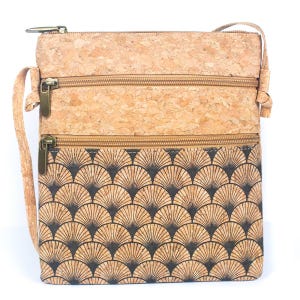 May include: A cork crossbody bag with a natural cork upper section and a lower section patterned with a black and tan fan design. It has three zipped compartments and an adjustable strap. The bag is made of cork.