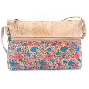May include: A crossbody bag with a floral pattern and a cork top. The bag features a colorful floral print with red, blue, and yellow flowers. The top of the bag is made of light brown cork material. The bag has a zipper closure and a long strap.