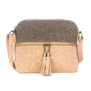 May include: A crossbody bag made of cork material. The top section is a dark brown speckled pattern, while the bottom is a lighter tan color. It features a zipper closure, a long strap, and a decorative tassel.
