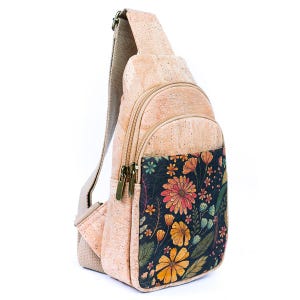 May include: A sling backpack crafted from light tan cork material featuring a front pocket with a dark navy blue background printed with a colorful floral pattern of orange, yellow, and teal flowers and green leaves, with beige fabric straps.
