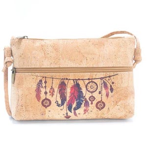 May include: A light brown cork crossbody bag with a zipper closure and adjustable strap. The bag features a colorful dreamcatcher design with feathers in shades of red, purple, and blue. The bag is rectangular in shape.
