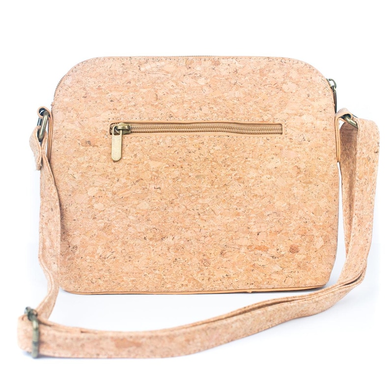 May include: A light brown cork crossbody bag with a zipper closure and adjustable strap. The bag has a rectangular shape with rounded corners and a textured surface. The strap and zipper are a matching light brown color.