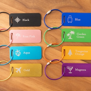 May include: Eight colorful luggage tags with different icons and text. The tags are black, rose pink, aqua, gold, blue, garden green, tangerine orange, and magenta. Each tag has a metal ring attached.