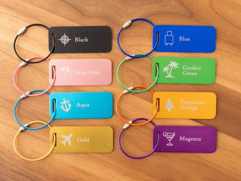 May include: Eight colorful luggage tags with different icons and text. The tags are black, rose pink, aqua, gold, blue, garden green, tangerine orange, and magenta. Each tag has a metal ring attached.