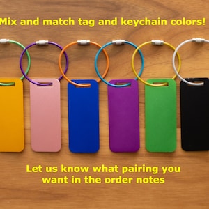 May include: Seven different colored keychains with matching colored tags. The keychains are silver and the tags are yellow, pink, blue, purple, green, and black.
