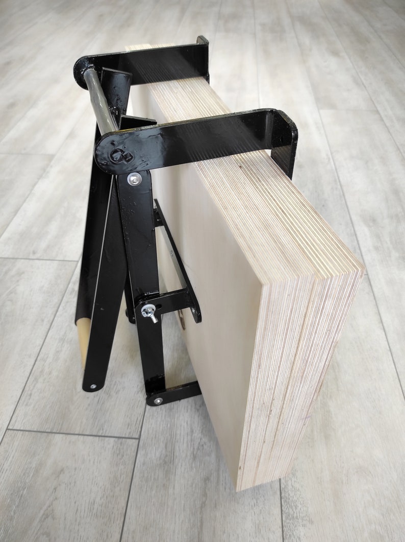 K&ouml;nnte beinhalten: Ein schwarzer Metallst&auml;nder mit einer Holzrolle und einem Stapel Sperrholzplatten. Der St&auml;nder ist so konzipiert, dass er die Sperrholzplatten h&auml;lt und transportiert.