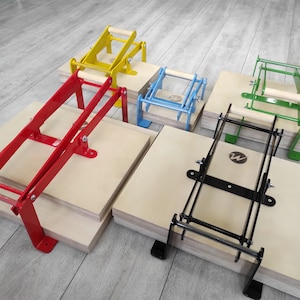 May include: Five different colored printing presses with wooden handles. The presses are made of metal and are stacked on top of wooden boards. The presses are used for printing on fabric, paper, and other materials.