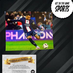 May include: Signed photograph of a footballer in a blue and white kit kicking a football on a green pitch. Includes a "Certificate of Authenticity" and the text "GET IN THE GAME SPORTS".