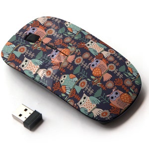 May include: A wireless computer mouse featuring a colourful owl and floral design. The mouse is dark blue with a variety of colours including orange, pink, green, and white.