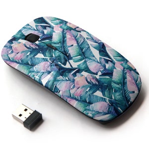 Pode incluir: Um rato sem fios para computador com um padrão de folhas tropicais. O rato é branco com um design de aquarela azul e rosa de folhas de palmeira. O rato vem com um pequeno receptor USB.