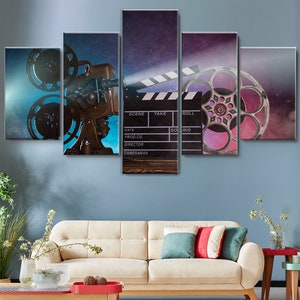 May include: A five-piece canvas print set featuring a vintage film projector, a clapperboard, and film reels. The background is a blue and purple gradient with stars. The clapperboard has the words "SCENE", "TAKE", "ROLL", "SOUND", "DATE", "PROD.CO.", "DIRECTOR", and "CAMERAMAN" written on it.
