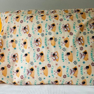 May include: A yellow and white pillowcase with a bowling theme. The pillowcase features a repeating pattern of bowling pins, bowling balls, and the words "Strike!" "Spare!" "Split!" and "Bowl!"