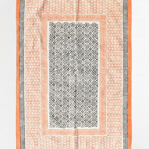 Könnte beinhalten: Ein rechteckiger Teppich mit einem geometrischen Muster in Schwarz und Weiß. Der Teppich hat einen Rand in einem pfirsichfarbenen Orange.