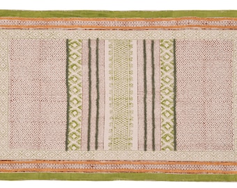 May include: A rectangular rug with a cream background and a green, orange, and brown geometric pattern. The rug has fringe on all four sides.