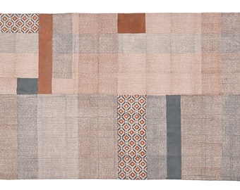 May include: A rectangular rug with a patchwork design featuring various shades of brown, gray, and beige. The rug has a geometric pattern in the center and fringe along the edges.