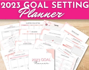 May include: A 2023 goal setting planner with pink and white pages. The planner includes sections for yearly goals, quarterly goals, monthly reviews, brain dump, idea bank, and action plans. The cover features the text "2023 Goal Planner" and "Follow Your Dreams!"