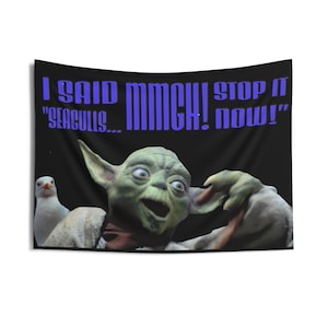 May include: A black tapestry featuring a green alien-like character with large ears and a surprised expression. The text in blue reads "I SAID MMCH! STOP IT 'SEAGULLS... NOW!'" A white seagull is visible on the left.