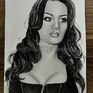 May include: A pencil drawing of a woman with long, wavy black hair and a black top. The drawing is in grayscale, with shading to create depth and dimension. The artist's signature and the year '24 are visible.