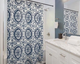 May include: A white shower curtain with a blue and white geometric pattern. The shower curtain is hanging in a bathroom with a white bathtub and a white vanity with a marble countertop.