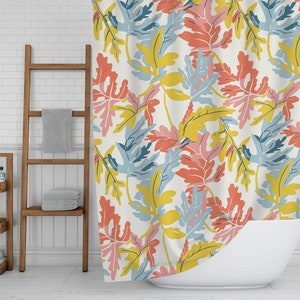 May include: A shower curtain with a repeating pattern of large, stylized leaves in coral, yellow, blue, and pink on a cream background. The curtain is hanging in front of a white bathtub. A wooden ladder and shelving unit are in the background.