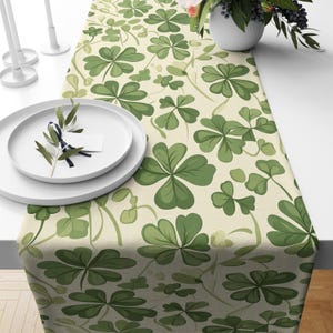 May include: A green and white table runner with a four-leaf clover pattern. The runner is made of a linen-like fabric and has a subtle sheen.