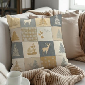 May include: Square throw pillow with a patchwork design featuring deer, trees, and leaf patterns in beige, gray, and gold. The pillow is on a light-colored sofa with other pillows and a knitted throw.