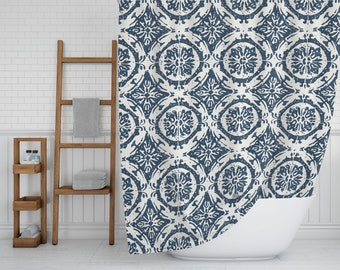 May include: A white shower curtain with a blue and white geometric pattern. The pattern is reminiscent of traditional tile designs. The shower curtain is hanging in a bathroom with a white tiled wall and a white bathtub.
