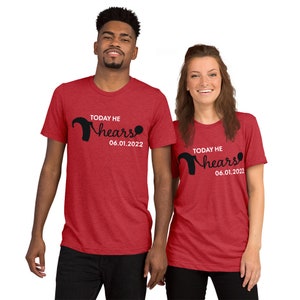 Puede incluir: Dos camisetas rojas con el texto "Today he hears" y la fecha "06.01.2022". El texto está en negro y la fecha en blanco. Las camisetas las llevan dos personas de pie una al lado de la otra.