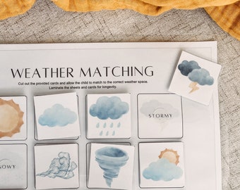 May include: A printable weather matching game for kids. The game features 12 weather cards with illustrations of sunny, cloudy, stormy, snowy, and windy weather. The cards are printed on white paper with blue and brown accents.