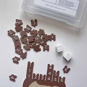 May include: A children's Hair Cut Game with a kid's head, numbered hair pieces, and dice. The game includes a clear plastic container with the text "HAIR CUT GAME" and instructions. The hair pieces are brown and the kid's head is tan.