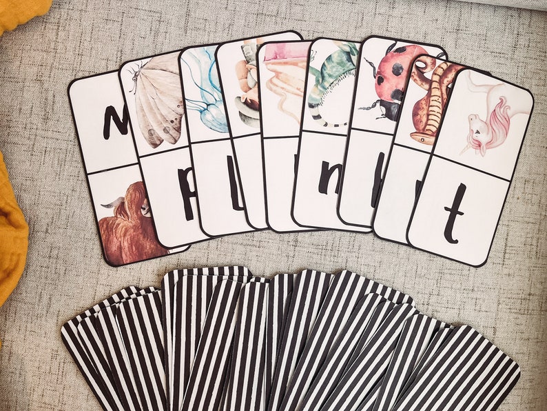 Pu&ograve; includere: Un set di carte bianche con lettere nere e illustrazioni colorate di animali. Le lettere sono M, P, L, N, W, T. Le illustrazioni includono una mucca, una farfalla, una medusa, un unicorno, una coccinella, un serpente e una lucertola.
