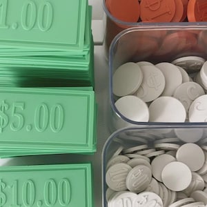 May include: Green plastic play money in denominations of $1.00, $5.00, and $10.00. Clear plastic containers hold white and orange game tokens, some with dollar sign and number imprints. Ideal for board games or educational play.