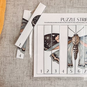 May include: A butterfly puzzle strip set with the text "PUZZLE STRIPS". The puzzle features a watercolor illustration of a butterfly, divided into numbered strips. The strips are placed on a white background. The numbers 1 and 4 are visible on the strips.