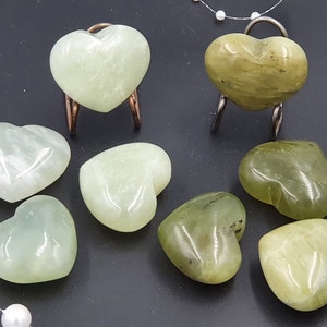 Può includere: Una collezione di pietre a forma di cuore in varie tonalità di verde. Alcuni cuori sono esposti su piccoli supporti metallici. Le pietre hanno una finitura lucida. Perle decorative sono infilate lungo il lato.
