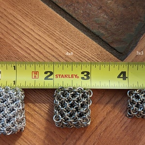 May include: Three silver chainmail squares of different sizes, measured with a yellow tape measure. The squares are labeled 5x5, 4x4, and 3x3.
